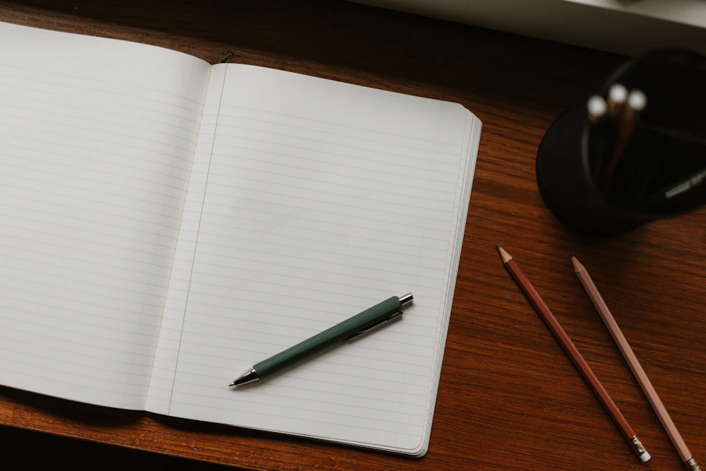 An open lined notebook and a pen on a wooden desk
